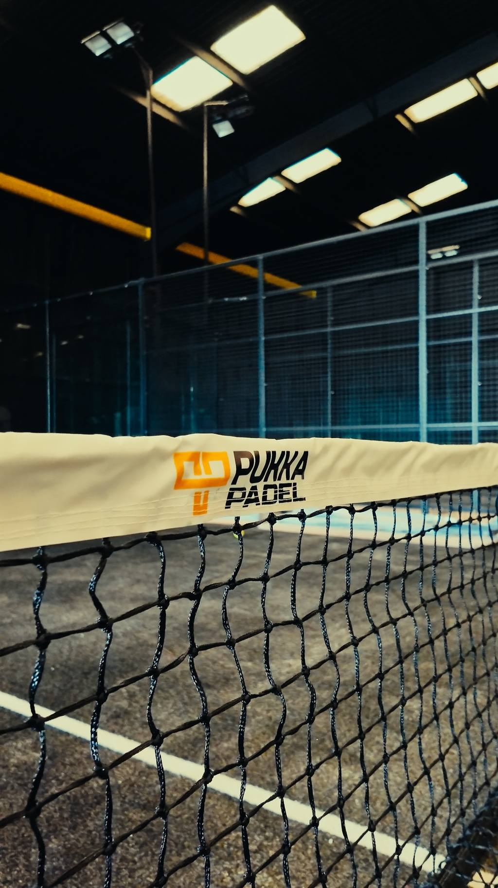 A padel net with branded tape stretched across the court.