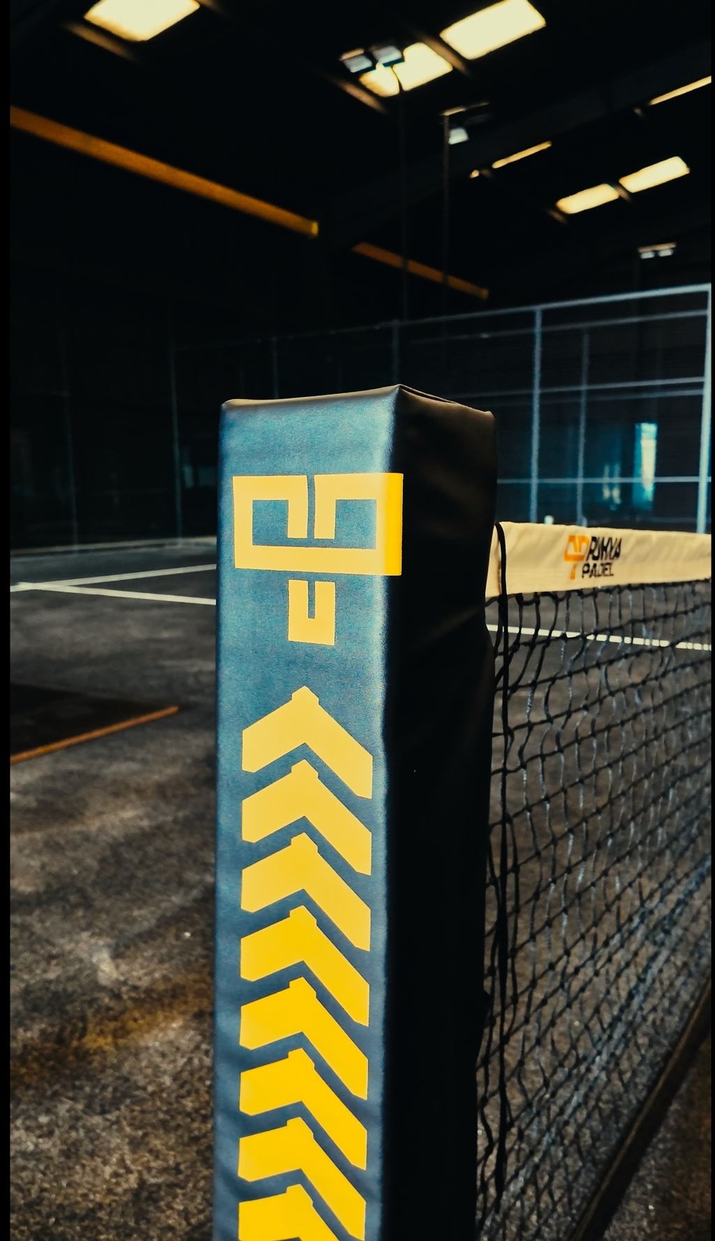 A padded net post finished in black and yellow, carrying a chevron pattern and monogram.